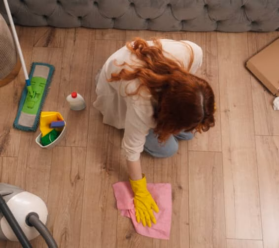 A woman wearing yellow gloves mops the floor, demonstrating cleaning activity in a domestic setting